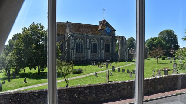 A historic church with a large clock tower, surrounded by a cemetery with well-maintained gravestones. - Matchbox is a delightful dog-friendly cottage in Winchelsea, East Sussex (Winchelsea)