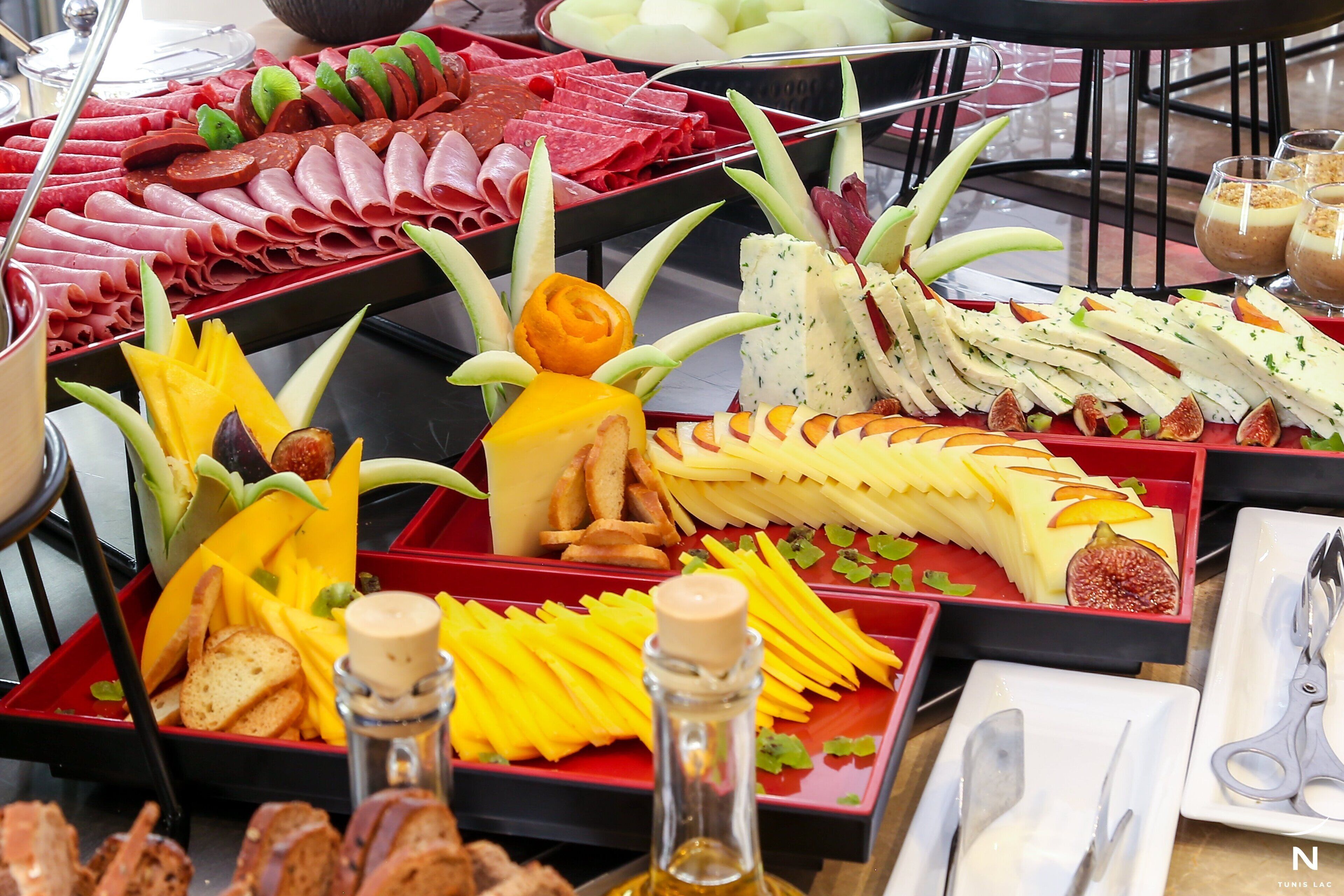 A buffet with various food items including meats, cheeses, and fruits.