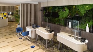 A modern reception area with a reception desk, seating, and a green wall with plants. - Novotel Tunis Lac (Tunis)