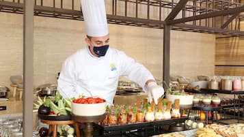 A chef in a white uniform and hat preparing food in a kitchen with various dishes and ingredients visible.