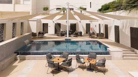 Una piscina al aire libre, sillones reclinables de piscina