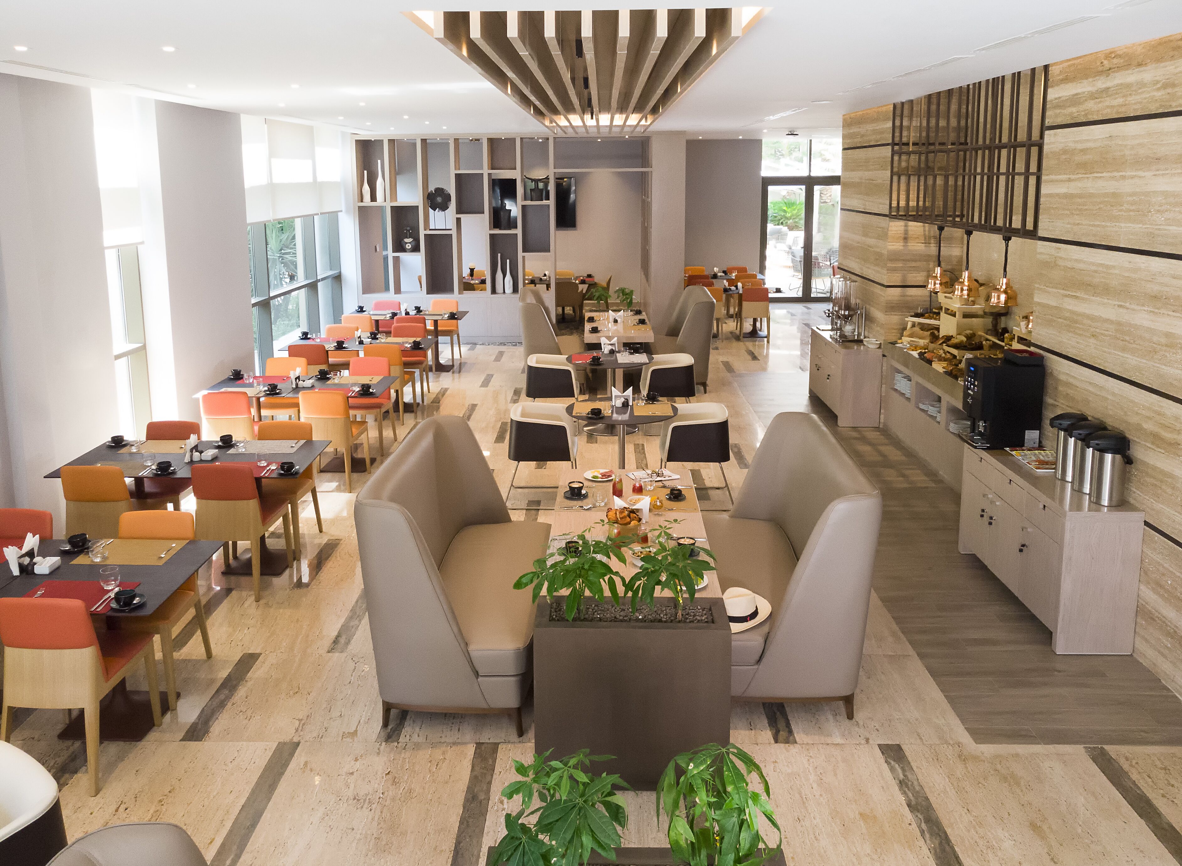 A modern restaurant with multiple seating areas, including booths and tables, and a bar counter with coffee machines.
