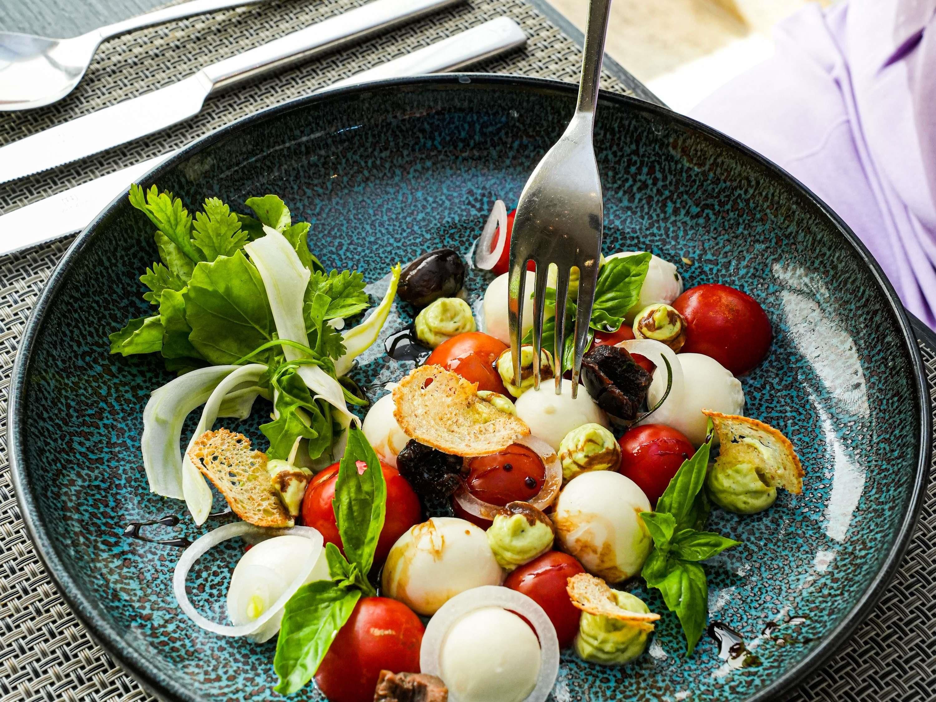 A plate of Caprese salad with tomatoes, mozzarella, basil, and bread.