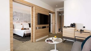 A hotel room with a bed, a TV, a desk with a phone and coffee maker, and a small table with a laptop and magazines. - Novotel Tunis Lac (Tunis)