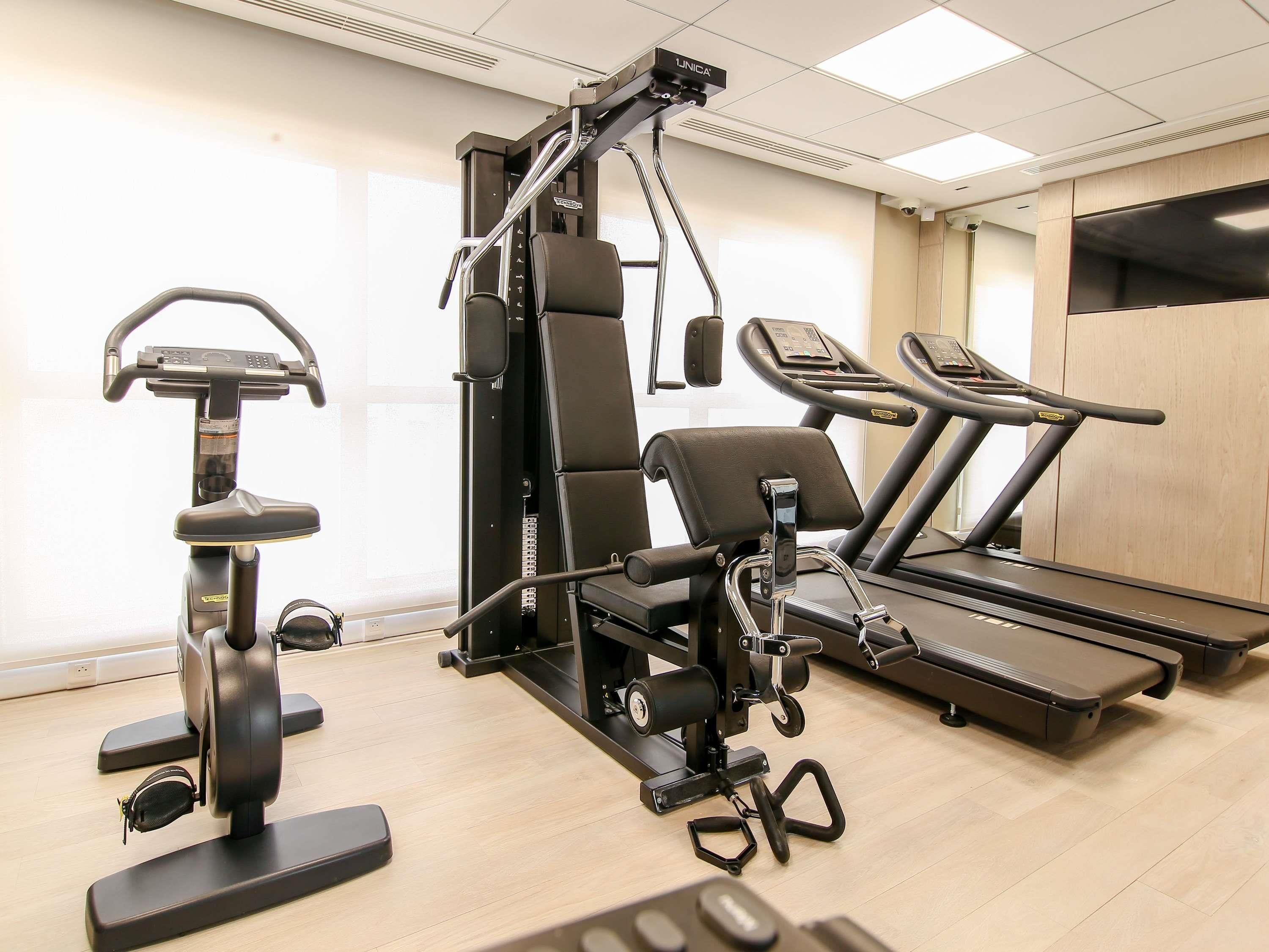 A gym with a stationary bike, weight bench, and treadmill.