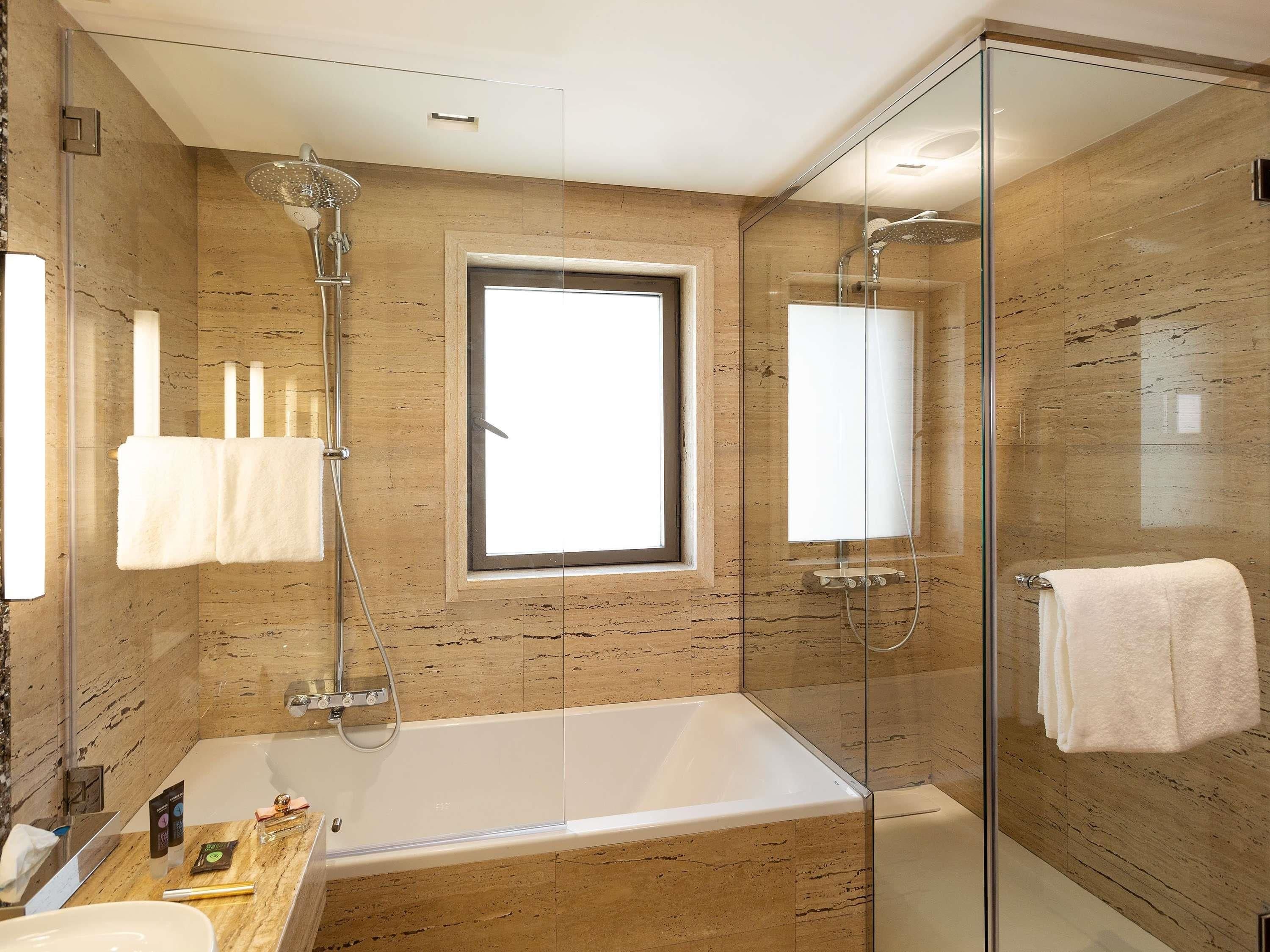 Une salle de bain moderne avec une douche à parois de verre, une baignoire et une fenêtre.