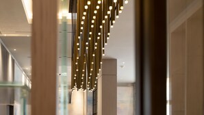 A modern interior with a glass railing, a hanging light fixture, and a view of a bathroom. - Novotel Tunis Lac (Tunis)