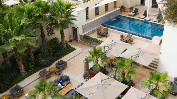 A rooftop pool area with lounge chairs, umbrellas, and palm trees. - Novotel Tunis Lac (Tunis)