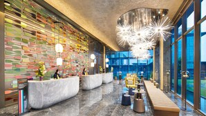 Un moderno vestíbulo de hotel con mostrador de recepción, zona de estar y amplias ventanas.