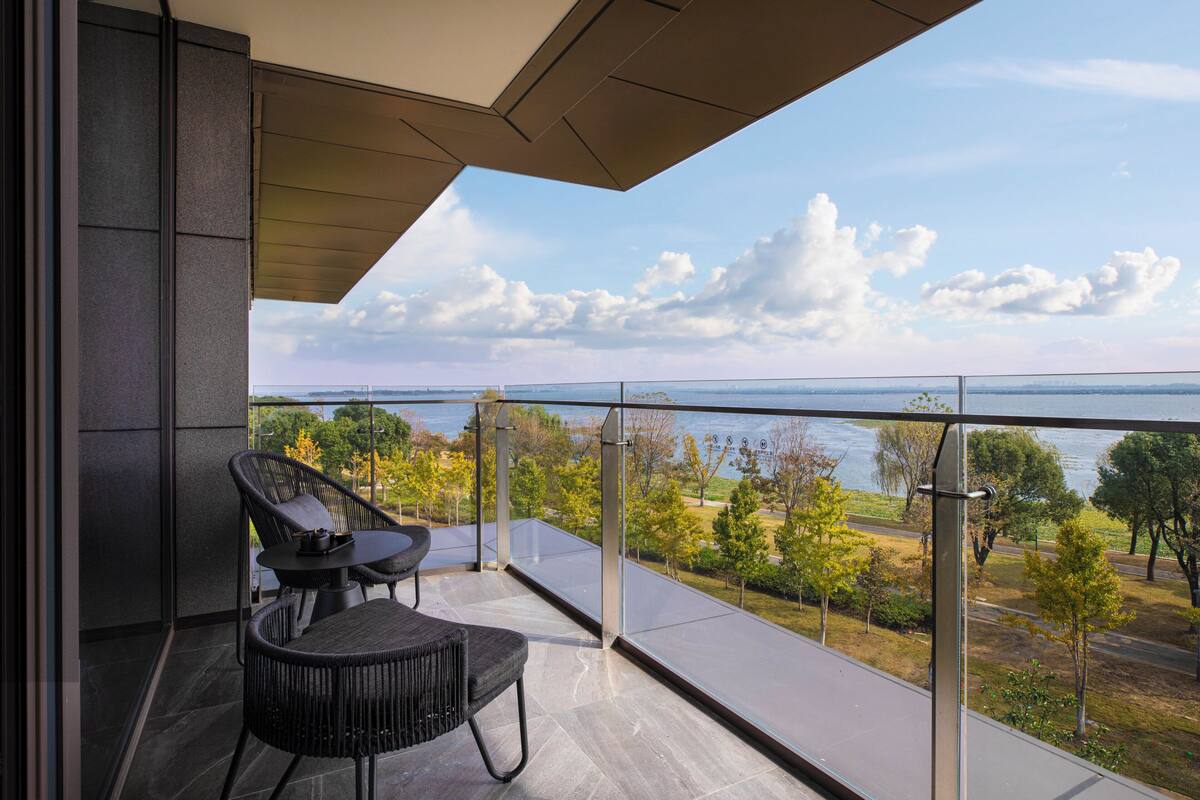A balcony with a view of a body of water and trees.