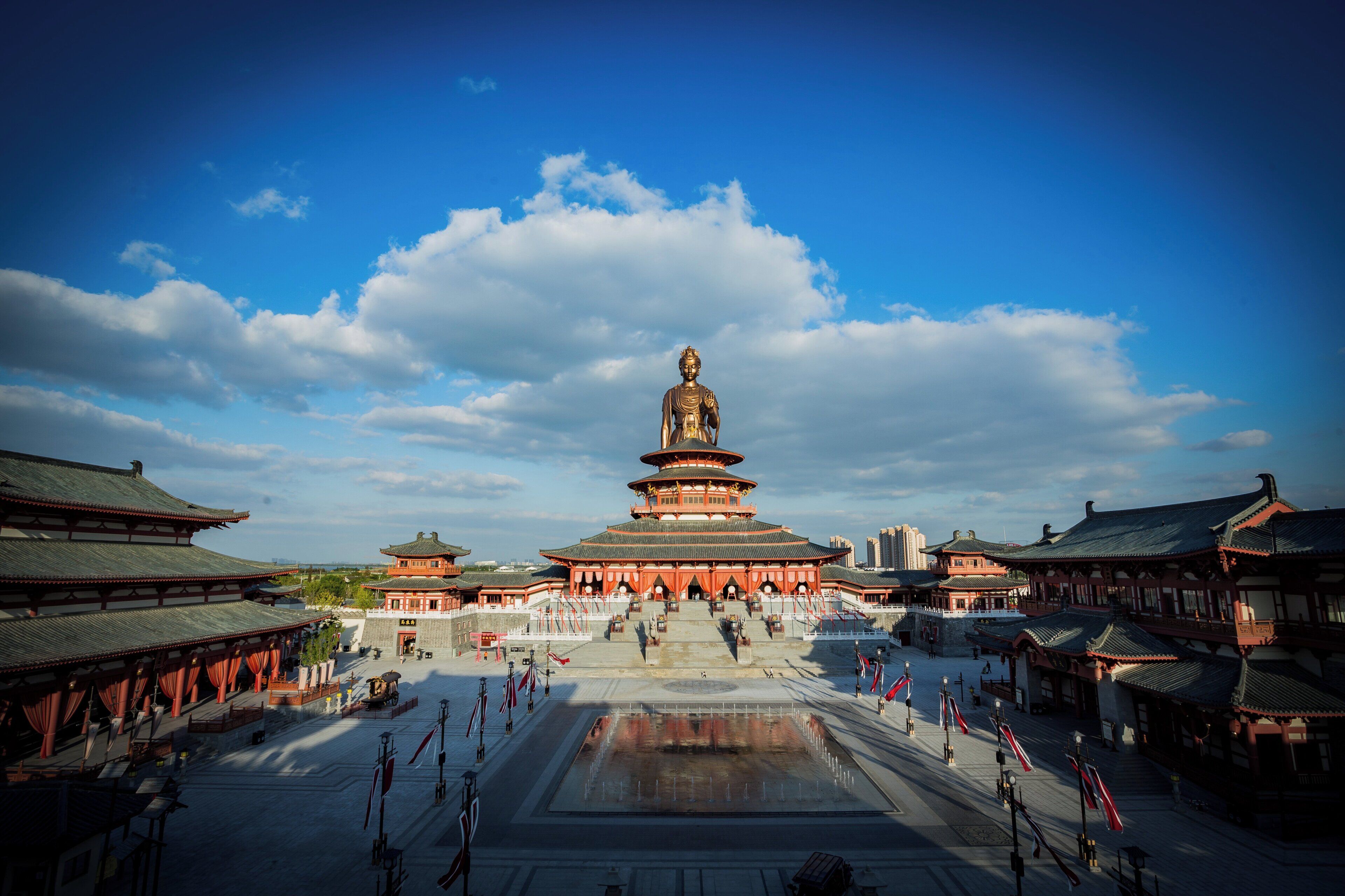Ein traditionelles chinesisches Gebäude mit einer großen Buddha-Statue in der Mitte, umgeben von kleineren Gebäuden und einem Innenhof.