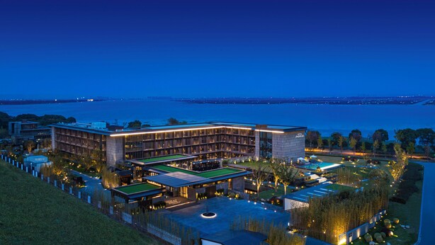 Un hotel moderno con piscina, cancha de tenis y vistas al agua.