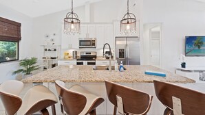 A modern kitchen with granite countertops, stainless steel appliances, and a central island with bar stools. - * Welcome to Relaxa * (Naples)
