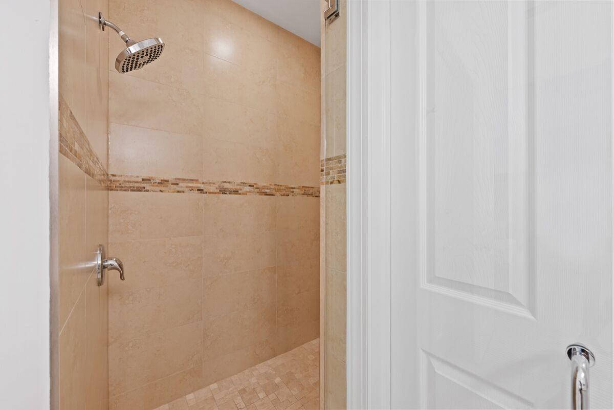 A bathroom with a shower, a door, and a tiled floor.