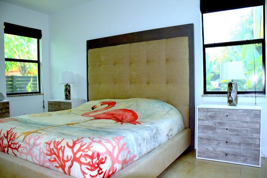 A bedroom with a bed, a nightstand, a dresser, and a window with a view of greenery.