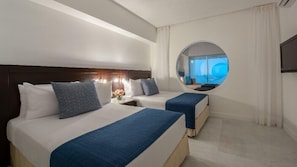 Ein Hotelzimmer mit zwei Betten, einem runden Spiegel und Meerblick durch ein Fenster.