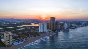 Eine Küstenstadt mit Hochhäusern, einem Strand und einem Sonnenuntergang.