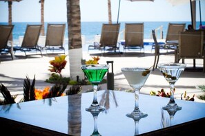 Eine Strandkulisse mit Liegestühlen und einem Tisch mit zwei Martini-Gläsern.