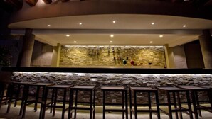 An outdoor bar area with wooden stools and a stone wall backdrop. - Tasteful Junior Suite with a Terrace and Private Beach Area (Marina Mazatlán)