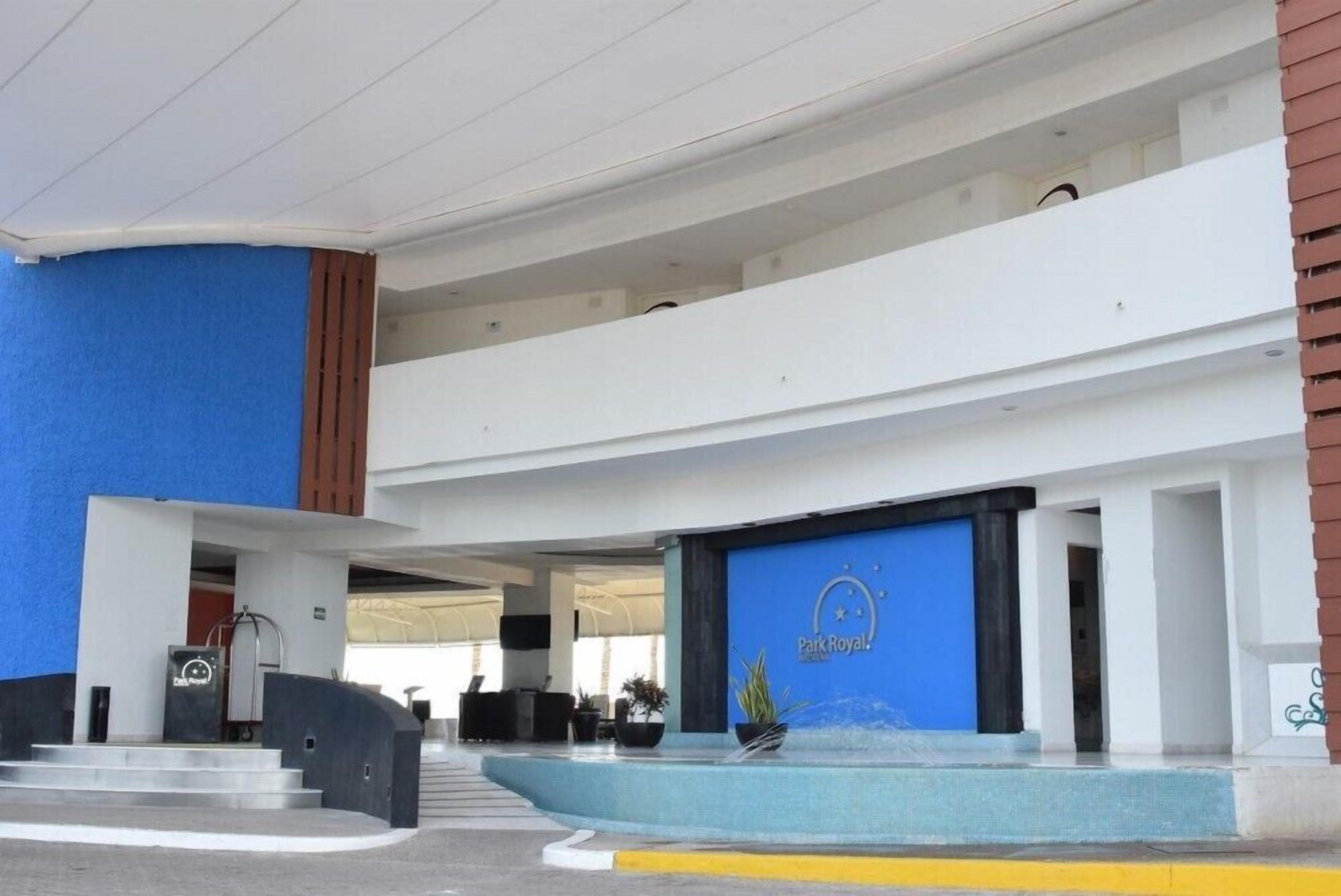 A hotel entrance with a blue facade, a reception desk, and a sign that reads "Park Royal."
