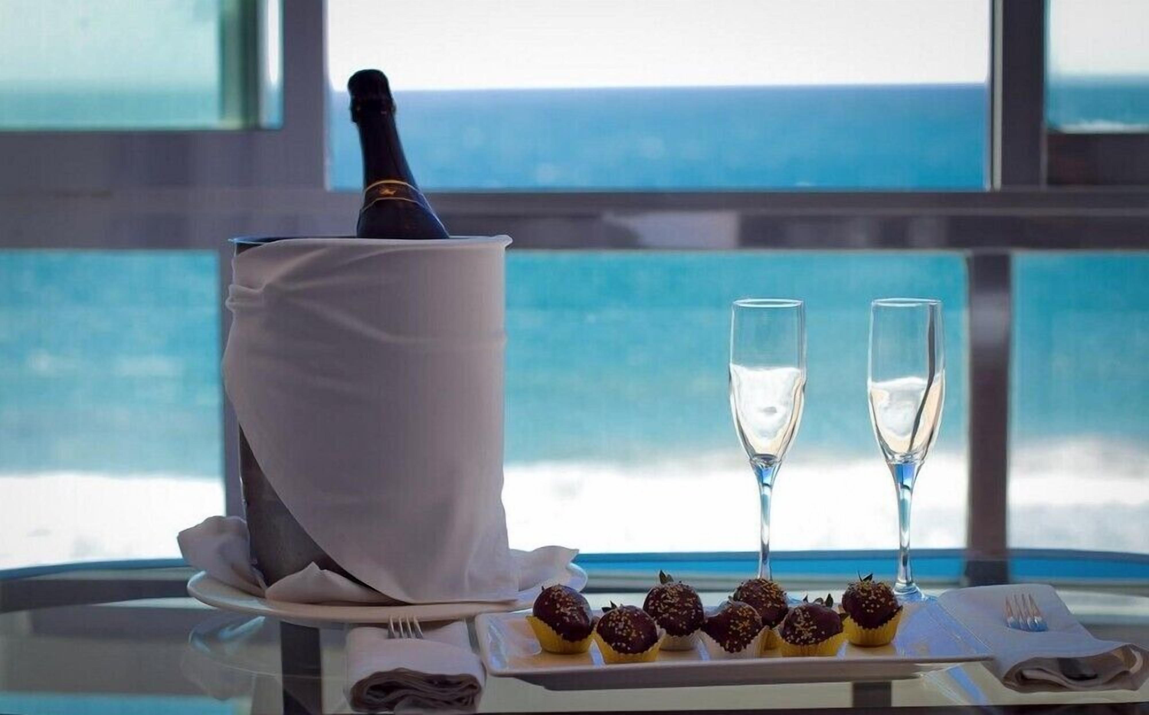 A table with a bottle of champagne, two glasses, and chocolate-covered treats.