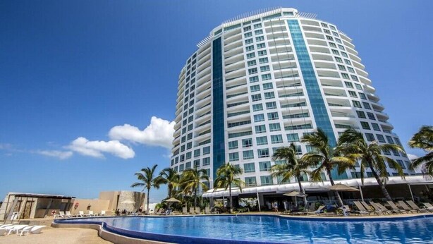 A tall, cylindrical hotel with a pool area in the foreground. - Private Junior Suite with a Short Ride Away from Beach (Marina Mazatlán)