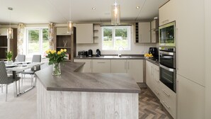 A modern kitchen with a central island, built-in appliances, and pendant lighting. - Hill View, Lilac Lodge (Wareham)