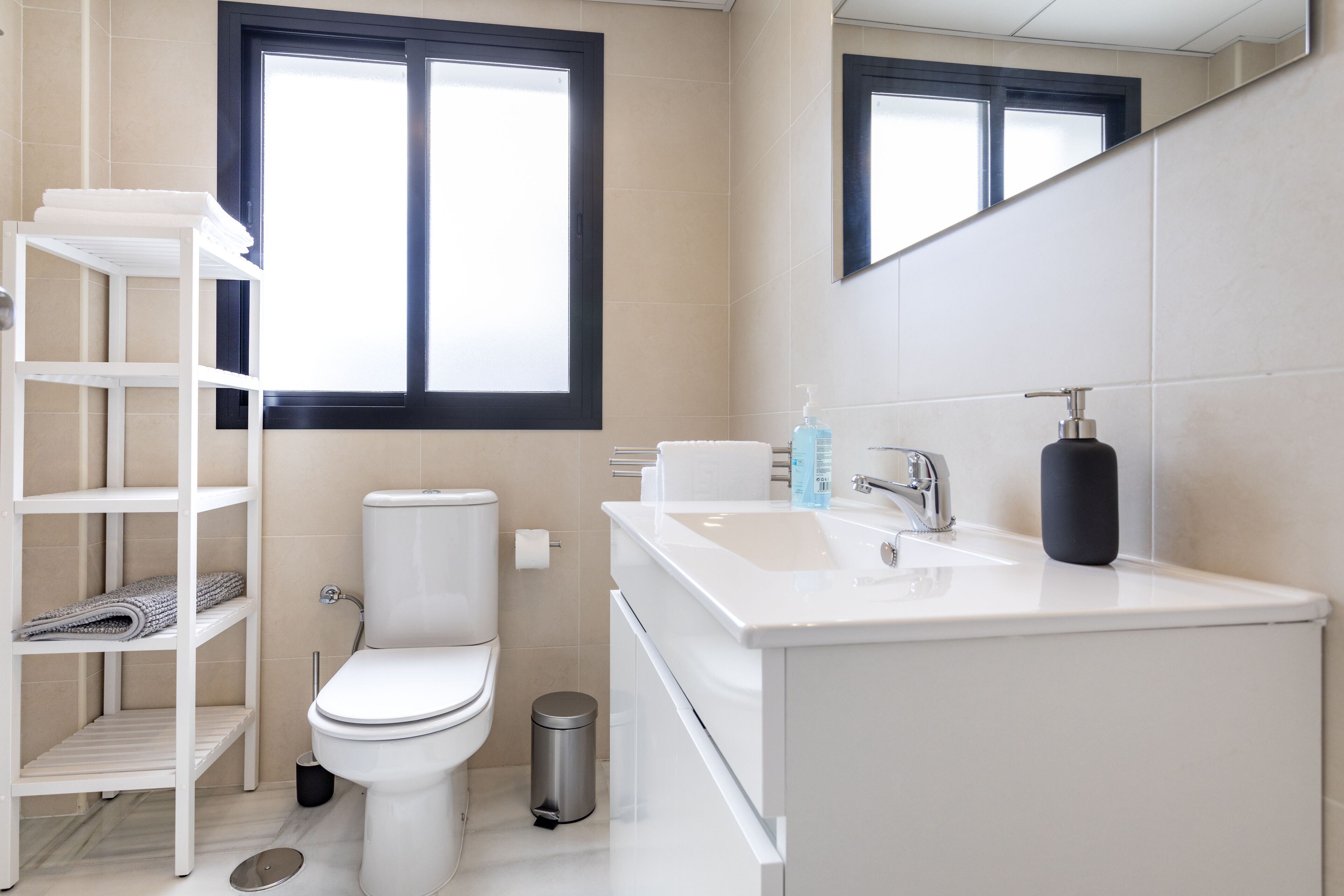 Un bagno moderno con il water, un lavandino e degli scaffali.