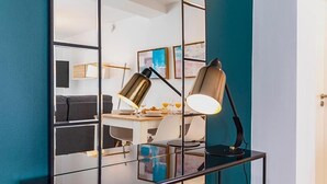 Une chambre moderne avec une cloison en verre, un bureau doté d’une lampe et des œuvres d’art accrochées au mur.