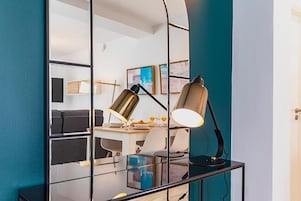 A modern room with a glass partition, a desk with a lamp, and artwork on the wall.