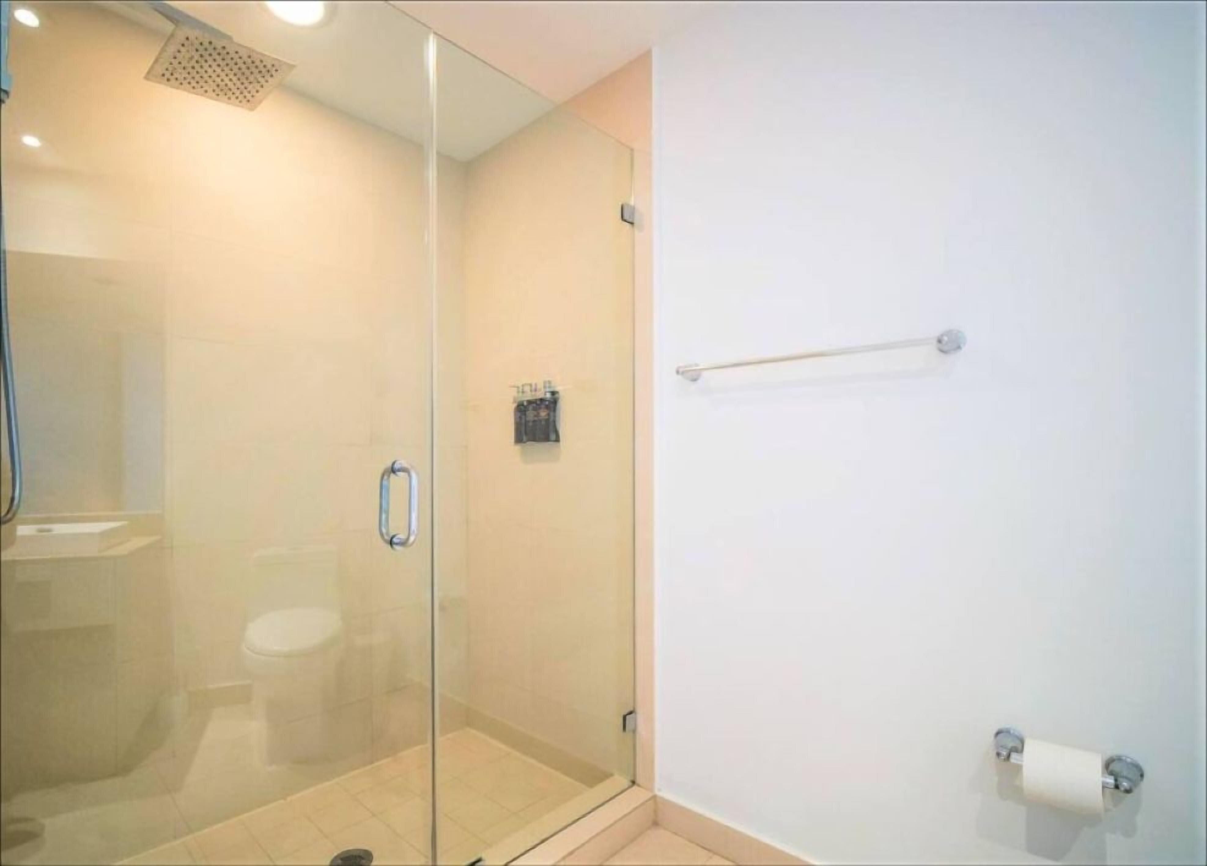 Cabina doccia in vetro con soffione a mano, porta in vetro e porta asciugamani a parete.