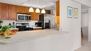A modern kitchen with wooden cabinets, stainless steel appliances, and pendant lighting. - Colorful, Modern Condo at the famed Biltmore (Palm Springs)