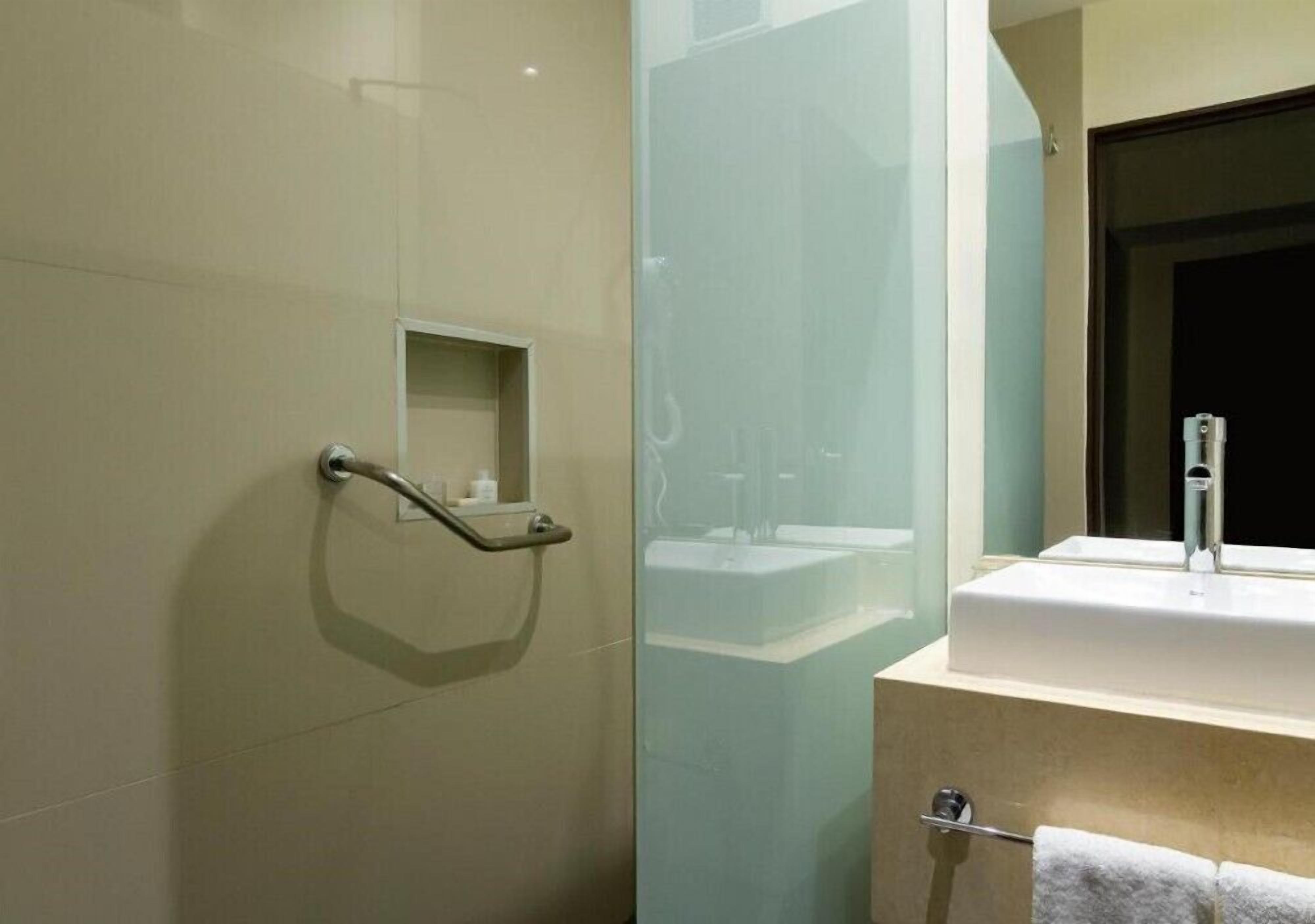 Une salle de bain moderne avec une douche à parois de verre, un lavabo blanc et un porte-serviettes.