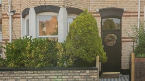 Une maison de style victorien, dotée d’une baie vitrée, d’une porte d’entrée ornée d’une guirlande et d’une façade en briques.