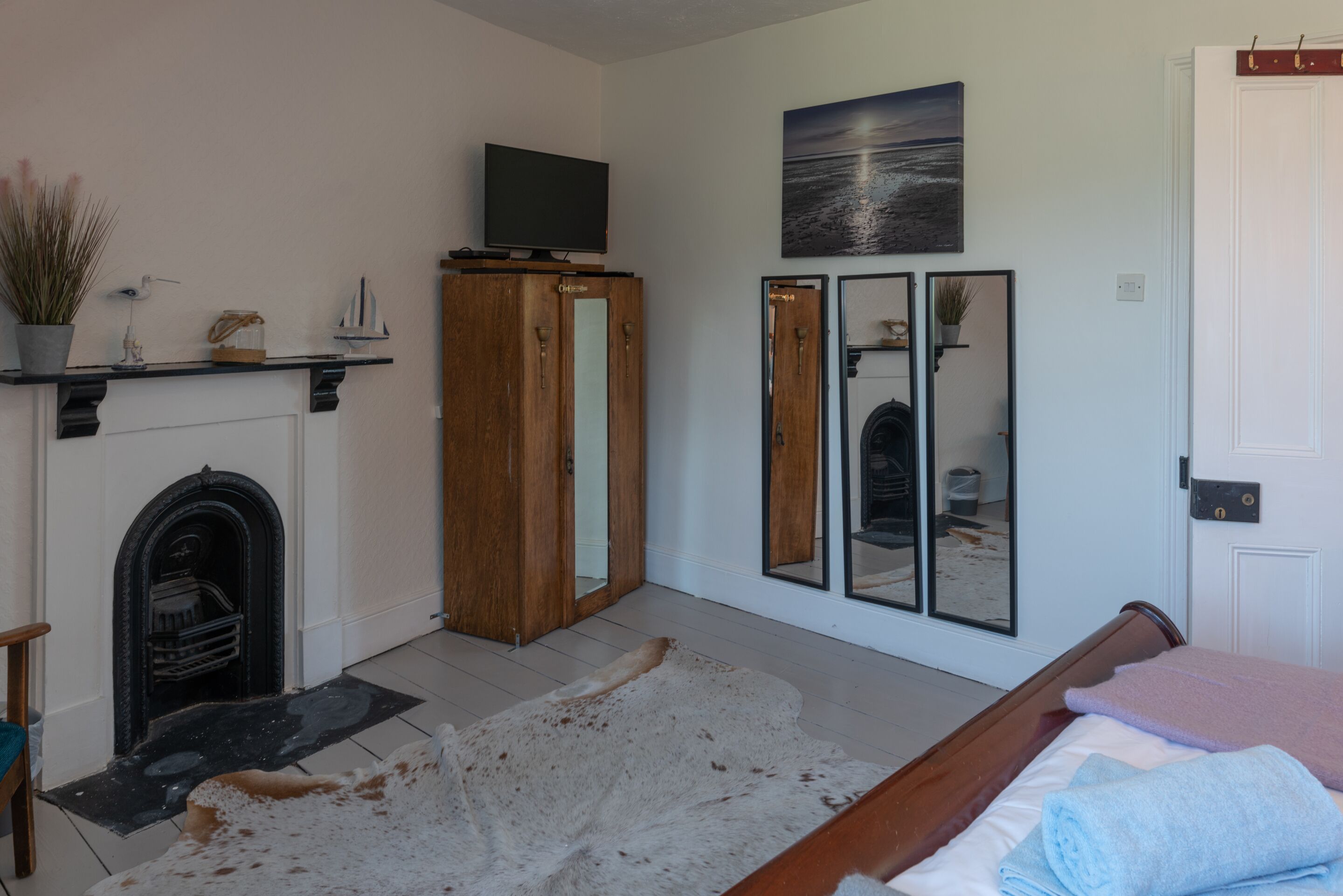 Ein Zimmer mit Kamin, einem Bett, einem Spiegel und einem Fernseher auf einem Standfuß.