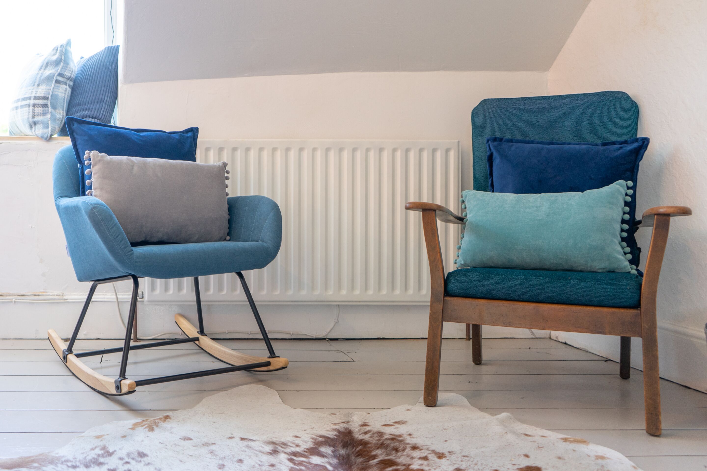 Two rocking chairs with blue cushions, a white radiator, and a cowhide rug.