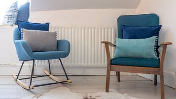 Two rocking chairs with blue cushions, a white radiator, and a cowhide rug.