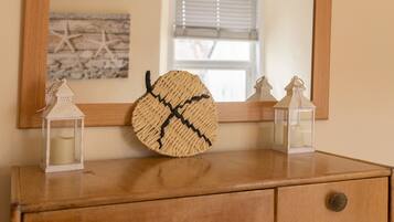 A wooden dresser with a mirror above it, two small lanterns, and a woven basket.
