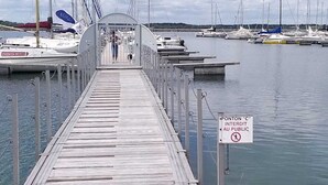 A wooden pier leading to a marina with boats docked.