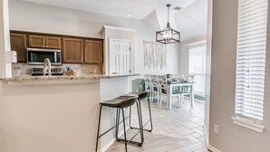 A modern kitchen with wooden cabinets, a microwave, and a bar stool. - Remodeled home in quiet neighborhood--kid friendly (Edmond)