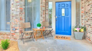 A blue door with a window above it, a small table with chairs, and a 'hello' mat at the entrance. - Remodeled home in quiet neighborhood--kid friendly (Edmond)