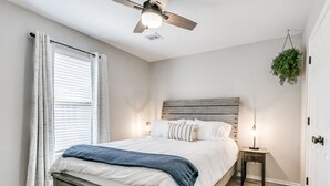 A bedroom with a bed, a nightstand, a ceiling fan, and a hanging plant. - Remodeled home in quiet neighborhood--kid friendly (Edmond)