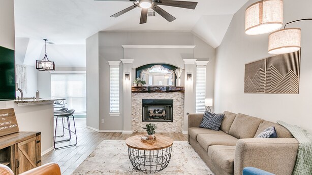 A spacious living room with a fireplace, a ceiling fan, and a modern coffee table. - Remodeled home in quiet neighborhood--kid friendly (Edmond)