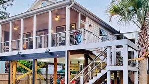 A two-story house with a balcony, a staircase, and a car parked in the driveway. - Luxury in a Prime Folly Location! Walk everywhere! (Folly Beach)