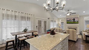 A spacious living area with a kitchen island, a dining table, and a fireplace. - Luxury in a Prime Folly Location! Walk everywhere! (Folly Beach)