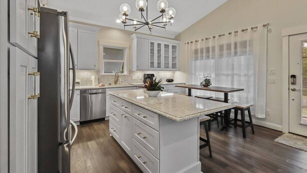 A modern kitchen with a central island, white cabinetry, and a dining area with a table and chairs. - Luxury in a Prime Folly Location! Walk everywhere! (Folly Beach)