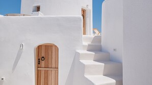 A white-washed building with a wooden door and steps leading to a higher level. - The Mill Haven Santorini (Santorini)