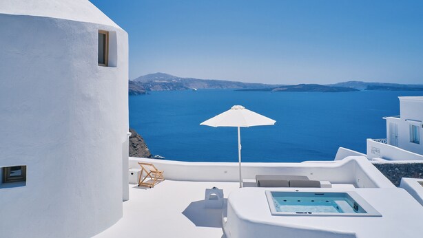 A white building with a pool, an umbrella, and a view of the sea. - The Mill Haven Santorini (Santorini)