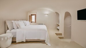 A bedroom with a bed, a window, a TV, and a staircase. - The Mill Haven Santorini (Santorini)