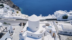 A white building with a round tower, surrounded by white buildings and a clear blue sea. - The Mill Haven Santorini (Santorini)
